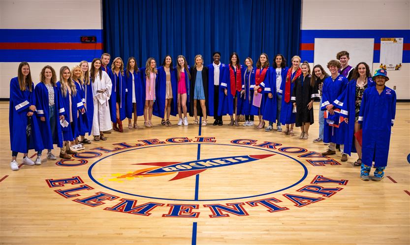 Seniors smile around the elementary school gym logo